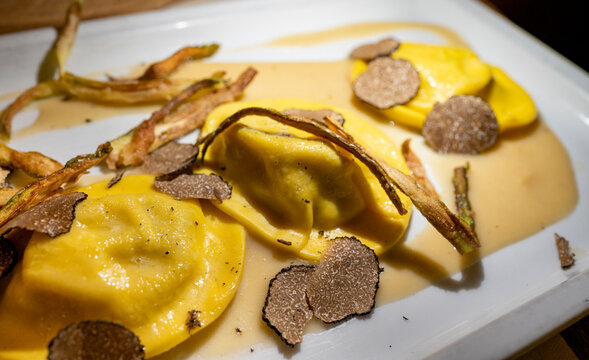 Italian food, fresh home made red potato stuffed pasta tortellacci or ravioli dumplings with summer black truffle and cripsy green asparagus, Parma, Emilia Romagna, Italy