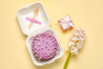 Plastic lunch box with tasty bento cake, gift and flowers on color background