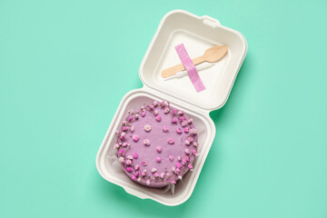 Plastic lunch box with tasty bento cake on turquoise background
