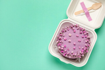 Plastic lunch box with tasty bento cake on turquoise background