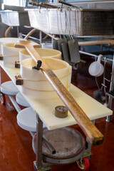 Fototapeta na wymiar Process of making wheels of parmigiano-reggiano parmesan cheese on small cheese farm in Parma, Italy