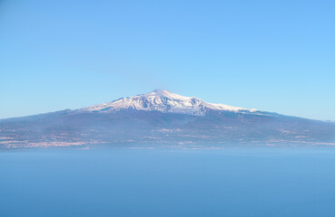 Aerial view of Mount Etna, an active volcano in Sicily, with snow capped mountain peak and Catania city, from the Mediterranean sea