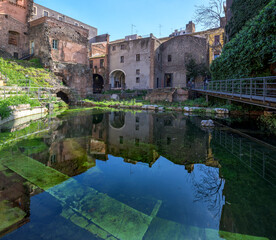 Roman theater, Catania, Italy. Old Roman amphitheater and Baroque style buildings, with a stage pond covered in vegetation and stone grandstands in Catania city center, Sicily, Italy