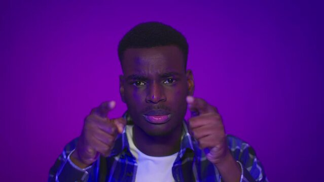 African Guy Pointing Fingers At Head And Camera, Purple Background