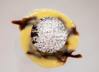 Tasty Italian dessert, small hot cake with chocolate and white gravy on white plate