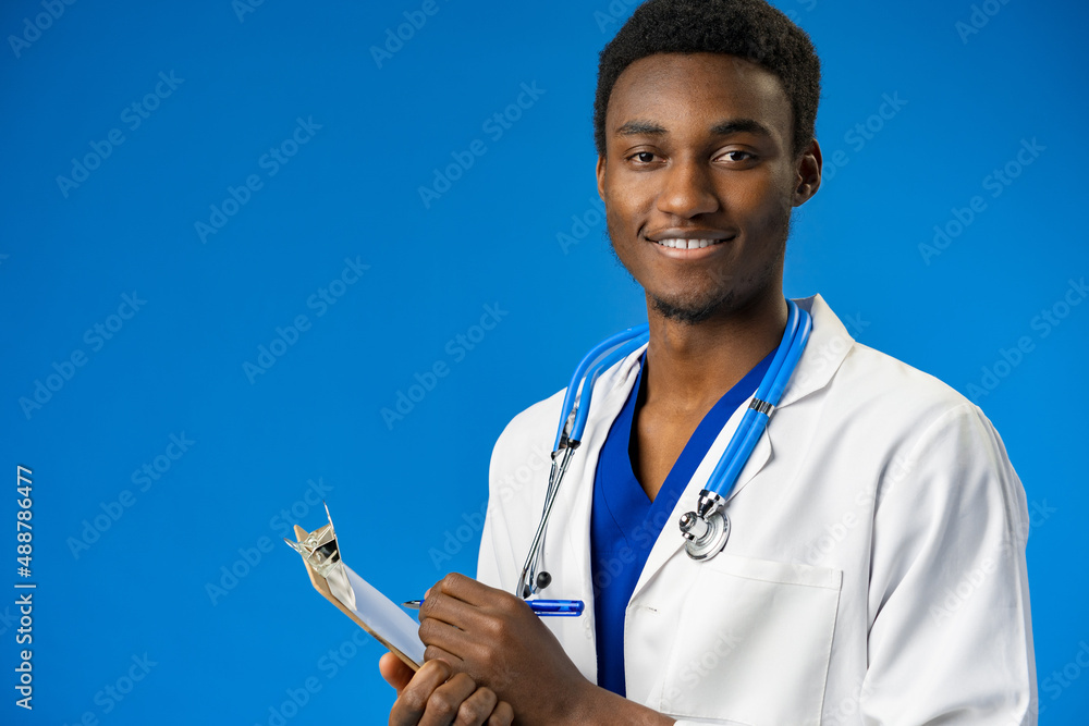 Wall mural Confident black doctor posing over blue studio background.