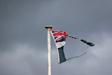 A ripped and tattered Union Jack flag flies on a windy winters day. 