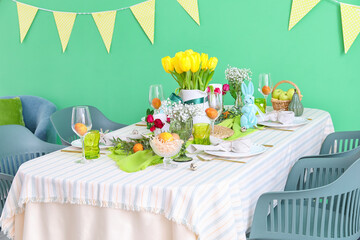 Stylish festive table setting for Easter celebration near color wall