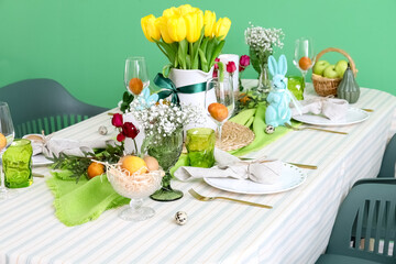 Stylish festive table setting for Easter celebration near color wall