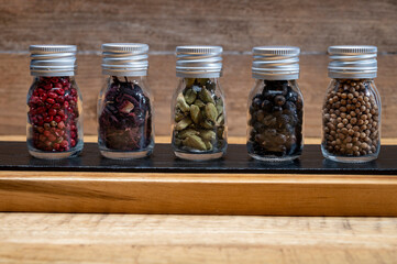 Professional set of gin spices in small bottles, pink pepper, hibiscus flowers, juniper berries, cardamom and coriander seeds