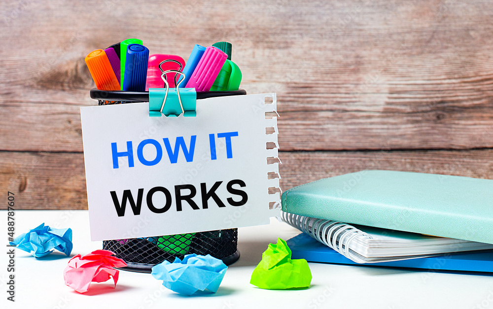 Poster on the desktop and against the background of a wooden wall, there is a stand with multi-colored felt