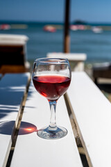 Drinking of cold rose wine in lounge bar on sunny sandy beach with blue sea water on background