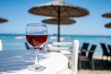 Drinking of cold rose wine in lounge bar on sunny sandy beach with blue sea water on background
