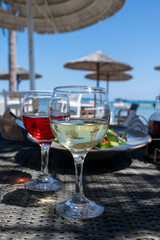 Drinking of cold rose and white wines in lounge bar on sunny sandy beach with blue sea water on background