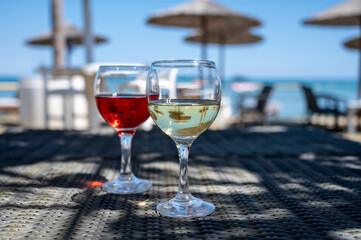 Drinking of cold rose and white wines in lounge bar on sunny sandy beach with blue sea water on background