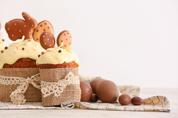 Tasty Easter cakes decorated with cookies and chocolate eggs on light background