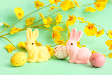 Cute Easter bunnies, eggs and blooming branch on color background
