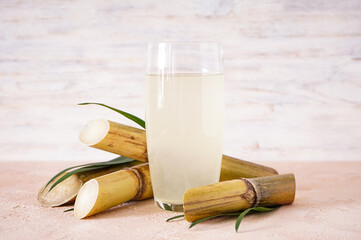 Sugarcane and fresh cane juice on wooden background.