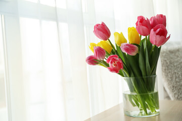 Vase with bouquet of tulips on table