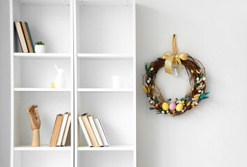 Beautiful Easter wreath and shelf unit near white wall