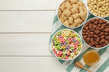 Different delicious breakfast cereals on white wooden table, flat lay. Space for text