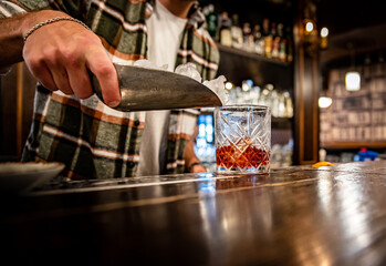 man hand bartender making glass negroni cocktail in bar