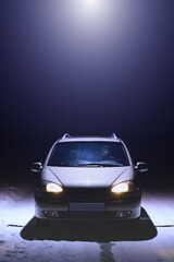 A beam of light coming from a ufo over a lone car parked on the side of the road. A man sits in a car and looks up at a UFO. Dark winter night. Vertical