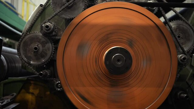 Industrial mechanism. Big metal orange gears rotating. Inside of factory.