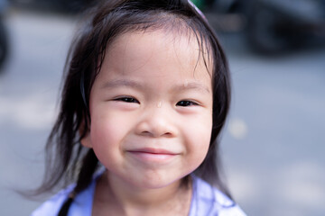 Closeup face child girl smile. Happy kid playing outside. Sweat dripped onto her forehead. On hot...