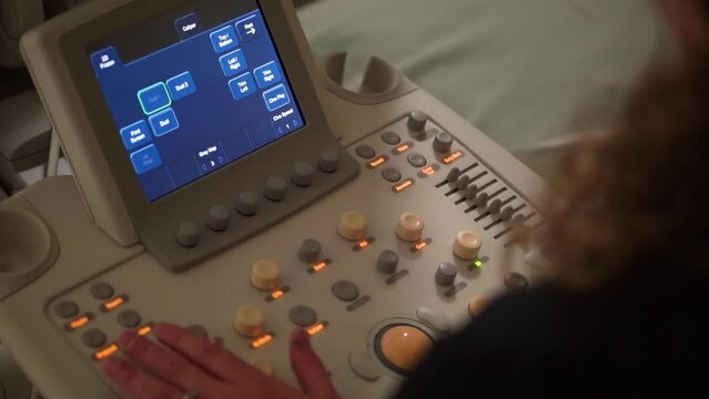 Woman manipulating medical equipment with screen, dials, and lights