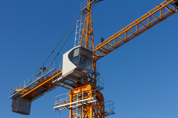 Tower crane against the blue sky. Tower crane operator's cabin. Crane operator at work.