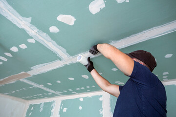 Worker glues mesh to drywall seams