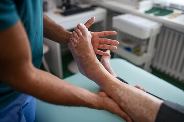 Close-up of physiotherapist exercising with senior patient's leg in a physic room.