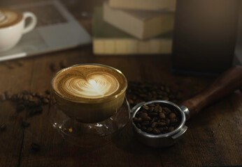 Glass of coffee with heart shape form milk on top, put on wooden desk,
