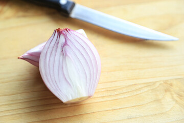 Slice red onion on cutting board for being ingredient in cooking