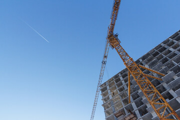 Residential building construction. Crane and building construction site against blue sky.