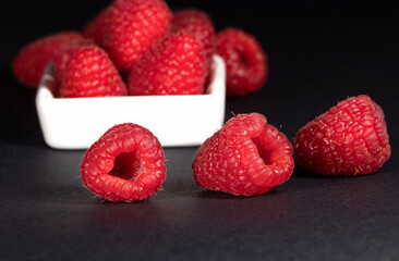 Raspberries in a white saucer on a black background