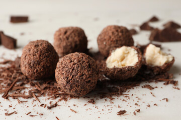 Many delicious chocolate truffles on light table, closeup