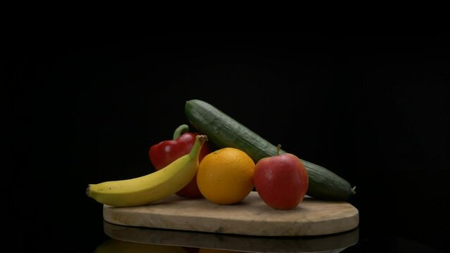 Arrangement of fruits coming into frame on a wooden cutting board