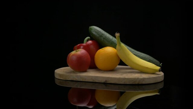 An arrangement of fruits slide through frame on a wooden cutting board.