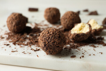 Many delicious chocolate truffles on white board, closeup