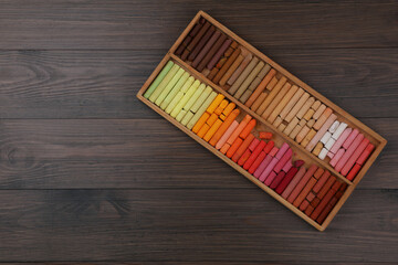 Drawing pastel set in box on wooden background, top view. Space for text