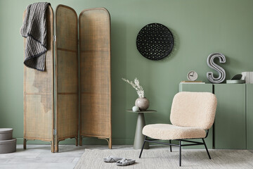 Creative living room interior composition with frotte armchair, folding screen, wooden commode and modern home accessories. Sage green wall. Template. Copy space. Real photo.
