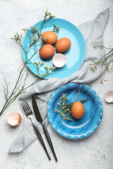 Stylish table setting with Easter eggs and flowers on light background