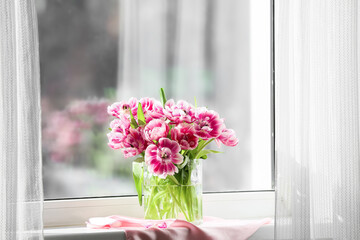 Vase of beautiful tulips on windowsill
