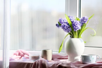 Foto op Plexiglas Vase with beautiful hyacinth flowers, cup of tea and candles on windowsill © Pixel-Shot