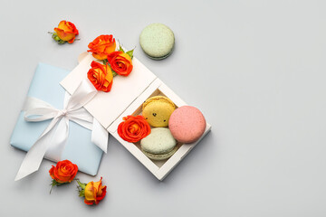 Fototapeta na wymiar Composition with sweet macaroons and rose flowers on white background. International Women's Day celebration