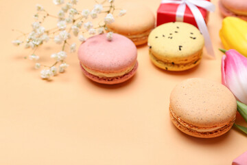 Sweet macaroons and flowers on color background, closeup