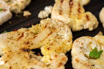 Cauliflower steak with spices cooks on a grill pan in close-up. Selective focus