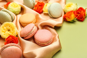 Composition with sweet macaroons and rose flowers on green background, closeup. International Women's Day celebration